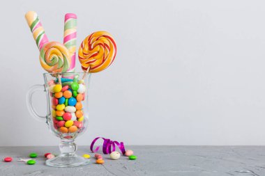 Masanın üzerinde açık arkaplanda renkli şekerler. Büyük kıvrımlı lolipoplar. Şekerci dükkanından leziz şekerlerle dolu yaratıcı bir kavanoz konsepti.