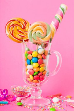 Masanın üzerinde açık arkaplanda renkli şekerler. Büyük kıvrımlı lolipoplar. Şekerci dükkanından leziz şekerlerle dolu yaratıcı bir kavanoz konsepti.