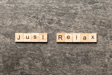 just relax word written on wood block. just relax text on table, concept.