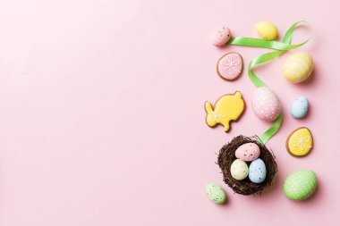 Colorful easter eggs in nest on table background with copy space top view.