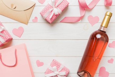top view photo of st valentine day decor shopping, bag, wine, bottle, envelope, gift, box, candy and red heart on colored background with empty space. Frame background.