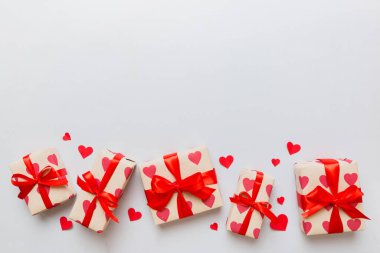 Top view photo of valentine day decorations gift box with red ribbon bow on colored background. Holiday gift boxes with top view.