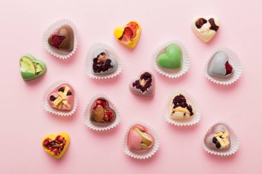chocolate sweets in the form of a heart with fruits and nuts on a colored background. top view with space for text, holiday concept.