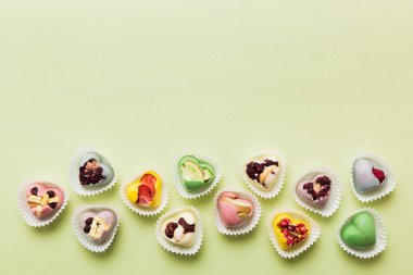 chocolate sweets in the form of a heart with fruits and nuts on a colored background. top view with space for text, holiday concept.
