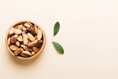 Fresh healthy Brazil nuts in bowl on colored table background. Top view Healthy eating bertholletia concept. Super foods.