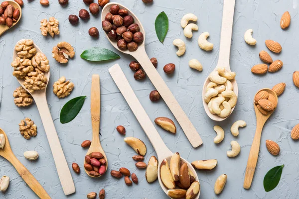 mixed nuts in white wooden spoon. Mix of various nuts on colored background. pistachios, cashews, walnuts, hazelnuts, peanuts and brazil nuts.