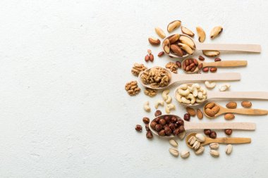 mixed nuts in white wooden spoon. Mix of various nuts on colored background. pistachios, cashews, walnuts, hazelnuts, peanuts and brazil nuts.