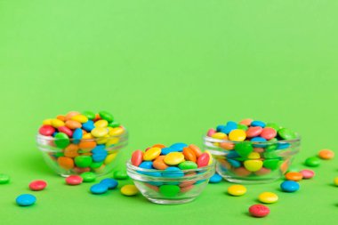 Renkli arka planda bir kasede çok renkli şekerler. Doğum günü ve tatil konsepti. Kopyalama alanı olan üst görünüm.