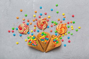 waffle cone full of assorted traditional candies falling out on colored background with copy space. Happy Holidays sale concept.