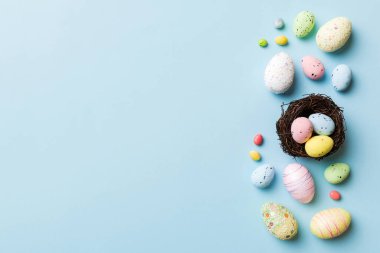 Colorful easter eggs in nest on table background with copy space top view.