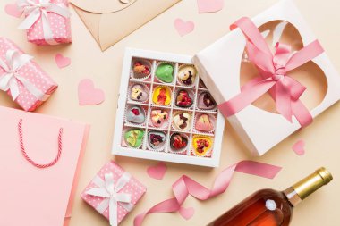 top view photo of st valentine day decor shopping, bag, wine, bottle, envelope, gift, box, candy and red heart on colored background with empty space. Frame background.