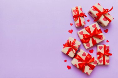 Top view photo of valentine day decorations gift box with red ribbon bow on colored background. Holiday gift boxes with top view.