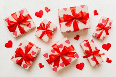 Top view photo of valentine day decorations gift box with red ribbon bow on colored background. Holiday gift boxes with top view.
