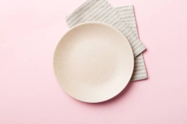 Renkli arka planda üst görünüm yiyecek için masa örtüsü üzerindeki boş yuvarlak beyaz tabak. Tasarımınız için boşluk olan peçeteye boş tabak.