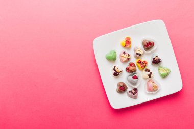 Plate with different chocolate on colored background. Assortment of fine chocolates top view vith copy space Health and obesity concept.