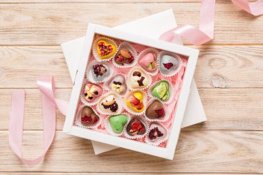 Holiday composition: sweet candy, with gift boxes with bow and chocolate hearts, photo template, background. Top View with copy space on colored background.