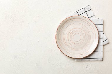 Renkli arka planda üst görünüm yiyecek için masa örtüsü üzerindeki boş yuvarlak beyaz tabak. Tasarımınız için boşluk olan peçeteye boş tabak.