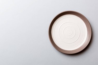 Renkli arka plan görüntüsünün üst görüntüsü yiyecek için boş yuvarlak beyaz tabak. Tasarımınız için alanı olan boş tabak.