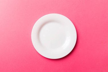 Renkli arka plan görüntüsünün üst görüntüsü yiyecek için boş yuvarlak beyaz tabak. Tasarımınız için alanı olan boş tabak.