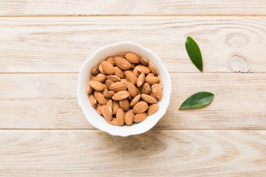 Fresh healthy Almond in bowl on colored table background. Top view.