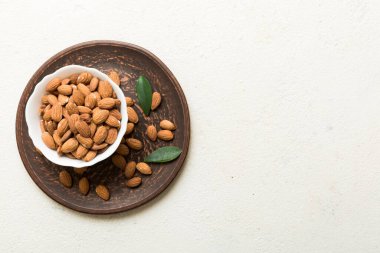 Fresh healthy Almond in bowl on colored table background. Top view.