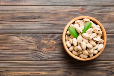 Fresh healthy Pistachios in bowl on colored table background. Top view. Healthy eating concept. Super foods.