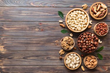 mixed nuts in wooden bowl. Mix of various nuts on colored background. pistachios, cashews, walnuts, hazelnuts, peanuts and brazil nuts.