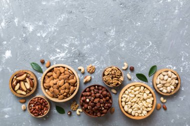 mixed nuts in wooden bowl. Mix of various nuts on colored background. pistachios, cashews, walnuts, hazelnuts, peanuts and brazil nuts.