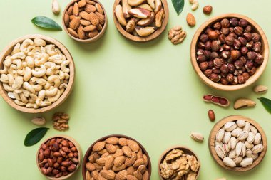 mixed nuts in wooden bowl. Mix of various nuts on colored background. pistachios, cashews, walnuts, hazelnuts, peanuts and brazil nuts.