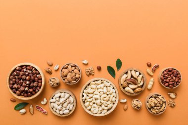 mixed nuts in wooden bowl. Mix of various nuts on colored background. pistachios, cashews, walnuts, hazelnuts, peanuts and brazil nuts.
