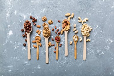 mixed nuts in white wooden spoon. Mix of various nuts on colored background. pistachios, cashews, walnuts, hazelnuts, peanuts and brazil nuts.