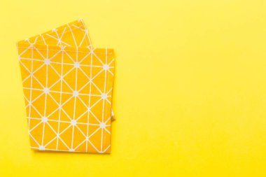 top view with yellow empty kitchen napkin isolated on table background. Folded cloth for mockup with copy space, Flat lay. Minimal style.