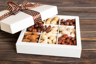 Various varieties of nuts lying in paper box on table background. Top view. Healthy food. Close up, copy space, top view, flat lay. Walnut, pistachios, almonds, hazelnuts and cashews.