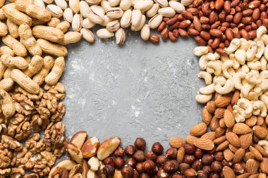 different nuts frame background. Close up, top view, flat lay with vopy space. Walnut, pistachios, almonds, hazelnuts and cashews.