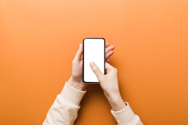 Mesajınız veya bilgi içeriğiniz için boş bir kopya ekranı olan akıllı telefonları tutan kadın ellerinin üst görünümü. üst görünümde telefon beyaz ekranı kullanan kadın eli.