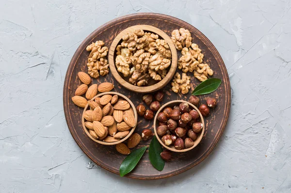 mixed nuts in wooden bowl. Mix of various nuts on colored background. pistachios, cashews, walnuts, hazelnuts, peanuts and brazil nuts.