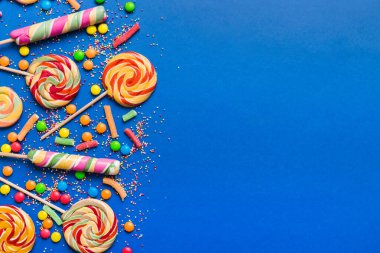 Lezzetli İştah açıcı Parti Aksesuarları Mutlu Yıllar Tatlı. Renkli arkaplanda farklı tipte şekerler, kopyalama alanı. Renkli doğum günü partisi geçmişi.