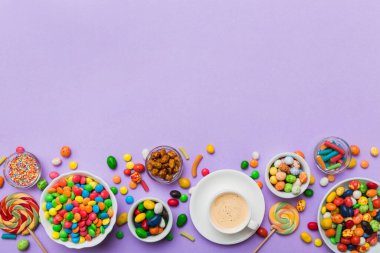 Coffee cup with chocolates and colored candy. Top view on table background with copy space.