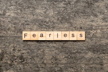 Tahta blokta korkusuzca yazılmış bir kelime. Çimento masasındaki korkusuz metin desing, konsept için.