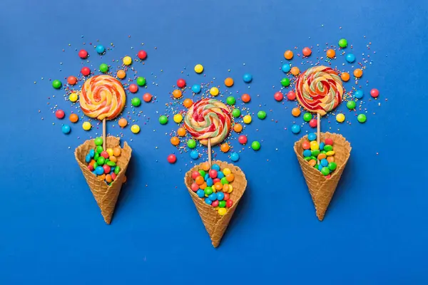 stock image waffle cone full of assorted traditional candies falling out on colored background with copy space. Happy Holidays sale concept.
