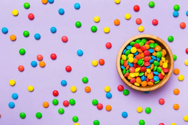 Multicolored candies in a bowl on a colored background. birthday and holiday concept. Top view with copy space.