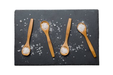 Beyaz arka planda izole edilmiş pek çok tahta kaşıkta tuz. Farklı tuzlu kaşıklar..