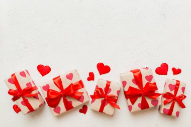 Top view photo of valentine day decorations gift box with red ribbon bow on colored background. Holiday gift boxes with top view.