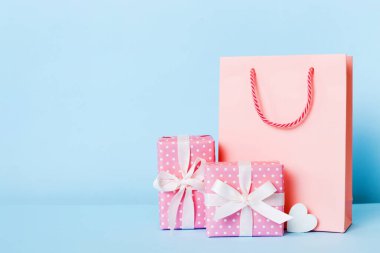 Shopping bag with gift box on colored background perspecrive view. Space for text holiday concept.