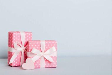 gift box with red bow and red heart on colored background. Perspective view. Flat lay.