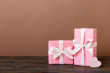 gift box with red bow and red heart on colored background. Perspective view. Flat lay.