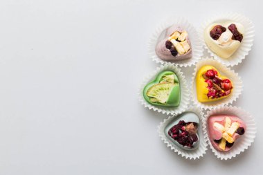 chocolate sweets in the form of a heart with fruits and nuts on a colored background. top view with space for text, holiday concept.