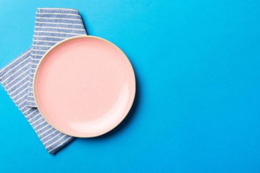 Renkli arka planda üst manzara. Yemek için masa örtüsü üzerine yuvarlak pembe tabak. Tasarımınız için boşluk olan peçeteye boş tabak.