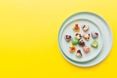 Plate with different chocolate on colored background. Assortment of fine chocolates top view vith copy space Health and obesity concept.