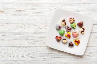 Plate with different chocolate on colored background. Assortment of fine chocolates top view vith copy space Health and obesity concept.
